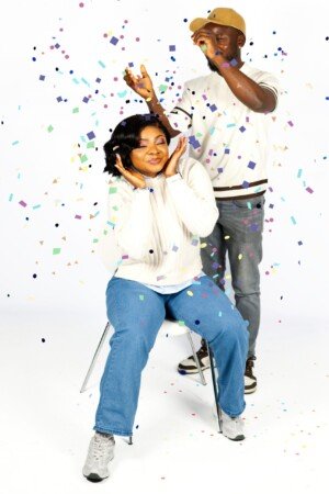 a man and woman sitting in a chair with confetti falling