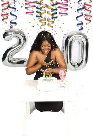 a woman sitting at a table with a cake and confetti