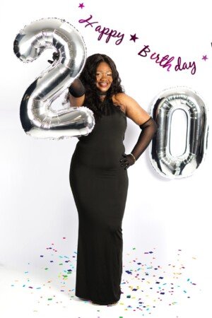 a woman in a black dress holding a silver balloon