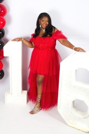 a woman in a red dress standing next to a large white number