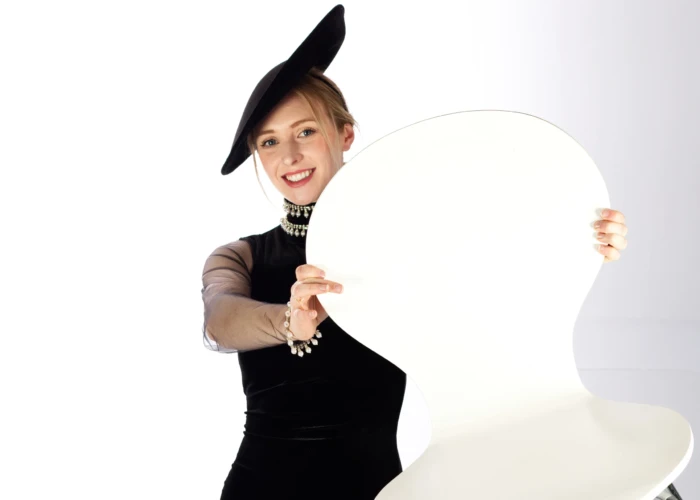 Female fashion model in stylish hat holding up a chair