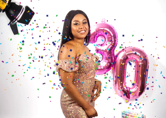 Afro caribbean lady smiling and wearing a gold dress celebrating her birthday at a photo studio